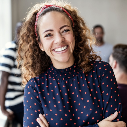 women in blue top with arms crossed, smiling while looking at the camera